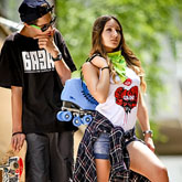 Teenage girl and boy with skateboards and roller skates outdoor portrait