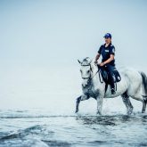 Police woman riding white horse in the sea