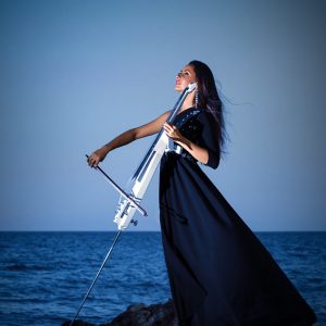 Beautiful woman playing cello on the sunset beach