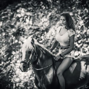 Young woman riding a horse in the forest