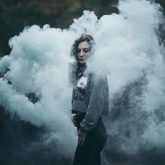 Girl portrait in clouds of colorful smoke