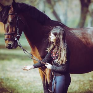 Girl with a brown horse walking in the forest