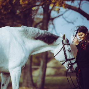 Girl with a white horse walking in the forest